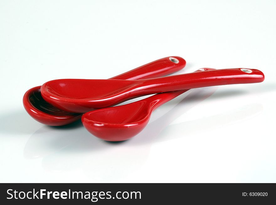 Three red teaspoons, isolated on white.