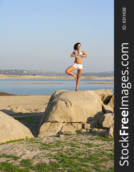 A Young Woman On Top Of A Rock Doing Yoga