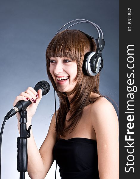 Woman in headphones Singing into Microphone.