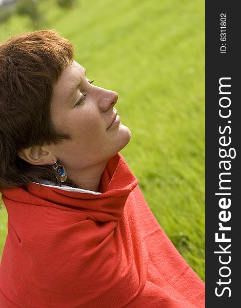 Closeup portrait of pretty redhead woman sitting on the grass