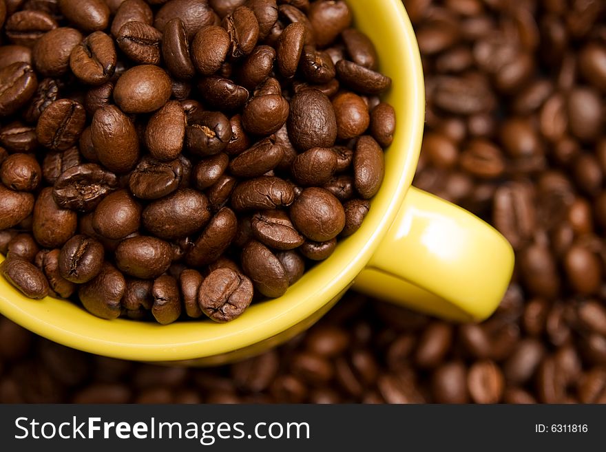 Coffee beans in a yellow cup on a background with nice DoF