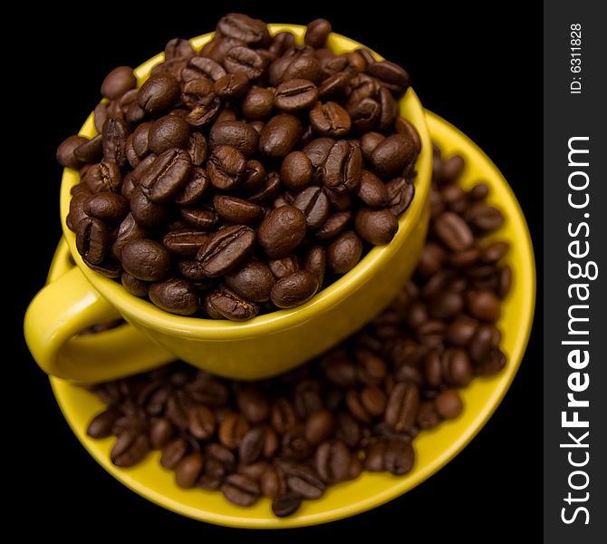 Coffee beans in a yellow cup isolated on a black background