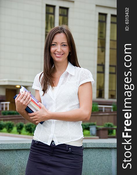 Happy student holds books in her hands.