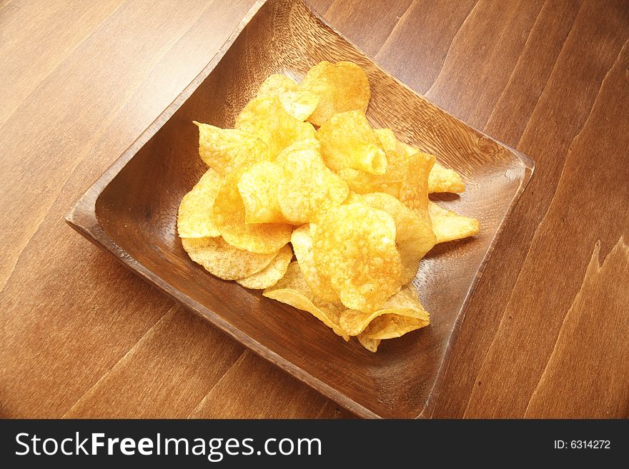 Crunchy potato chip in a wooden bowl. Crunchy potato chip in a wooden bowl