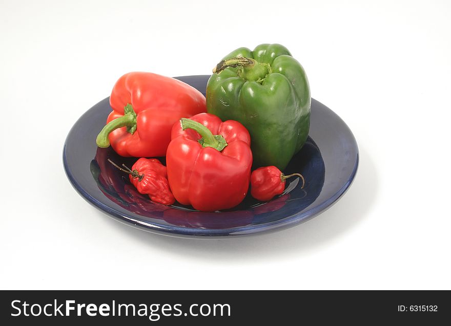 Isolated fresh assorted peppers on blue plate. Isolated fresh assorted peppers on blue plate