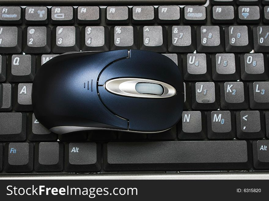 A wireless mouse put on keyboard of a laptop. A wireless mouse put on keyboard of a laptop.