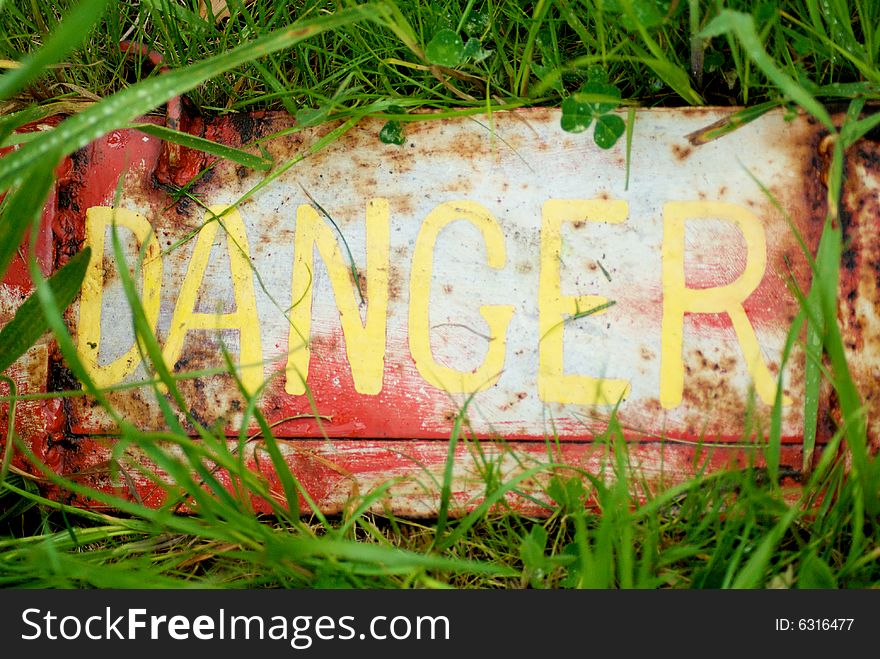 Danger sign slightly concealed in grass. Danger sign slightly concealed in grass