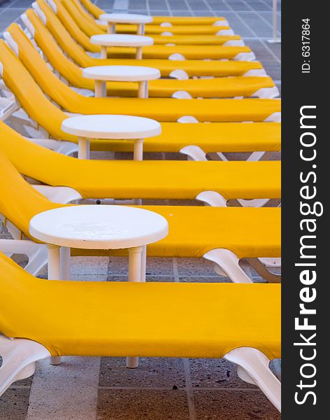Yellow loungers next to a swimming pool.