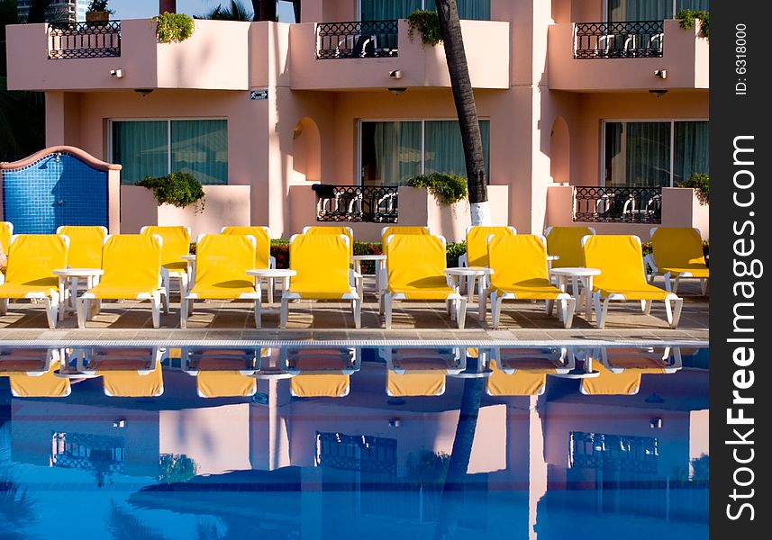 Yellow loungers reflecting in a swimming pool. Yellow loungers reflecting in a swimming pool.