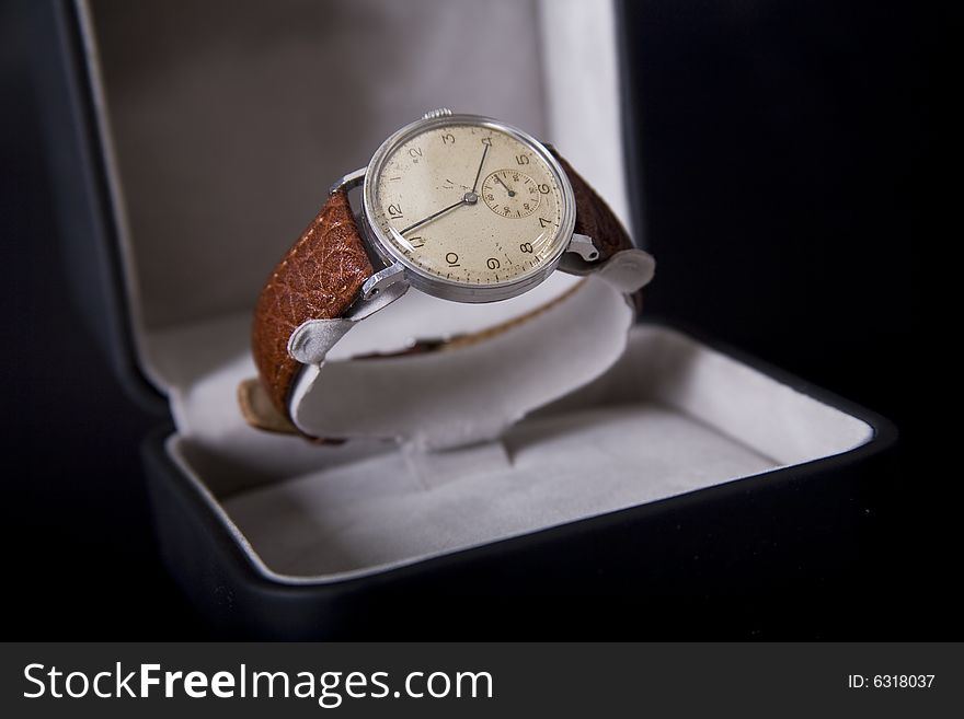 Old wristwatch in box on dark background