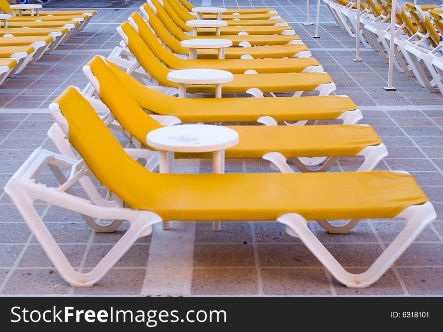 Yellow loungers next to a swimming pool.