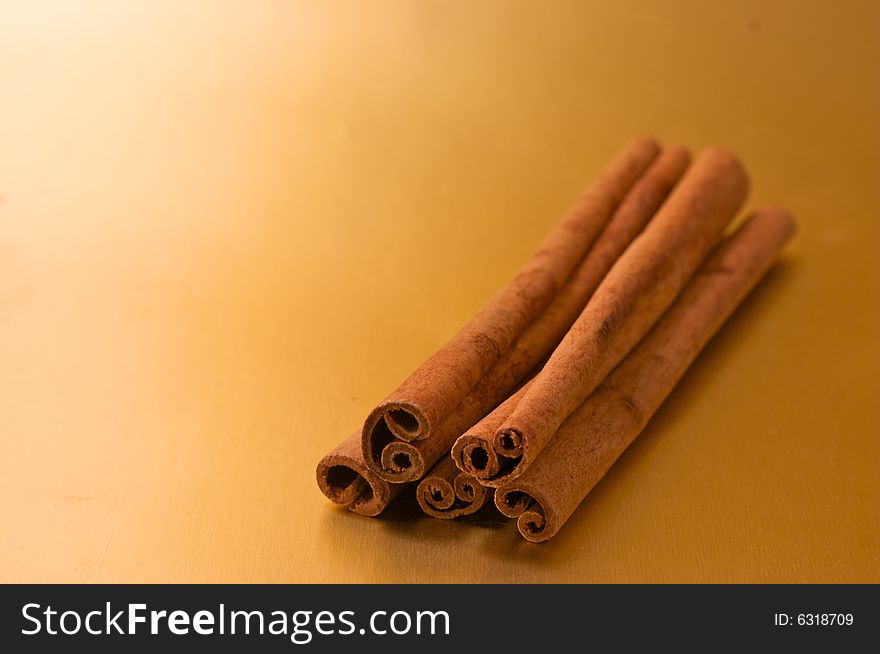 Cinnamon sticks stacked on a gold background