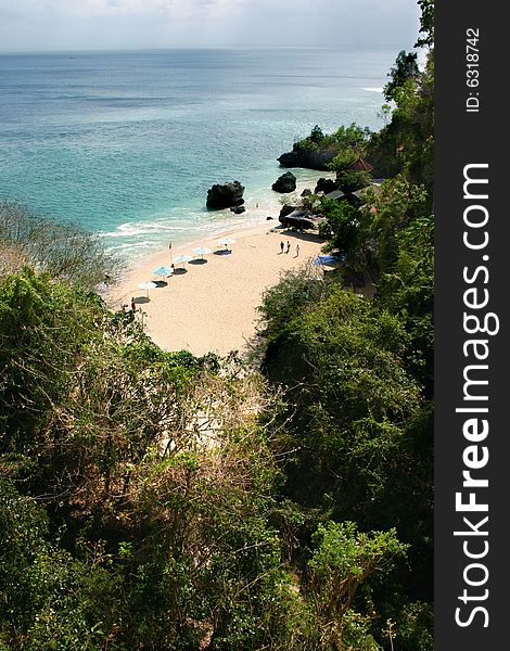 A beach with sunshades, green foliage and clear water. A beach with sunshades, green foliage and clear water.