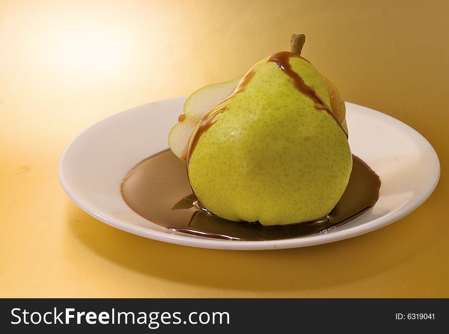 A sliced pear with chocolate sauce on a white plate