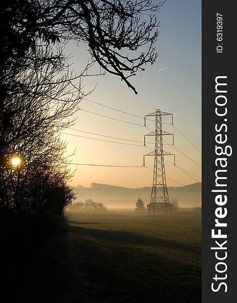 Electricity pylons at sunrise in a rural field. Electricity pylons at sunrise in a rural field