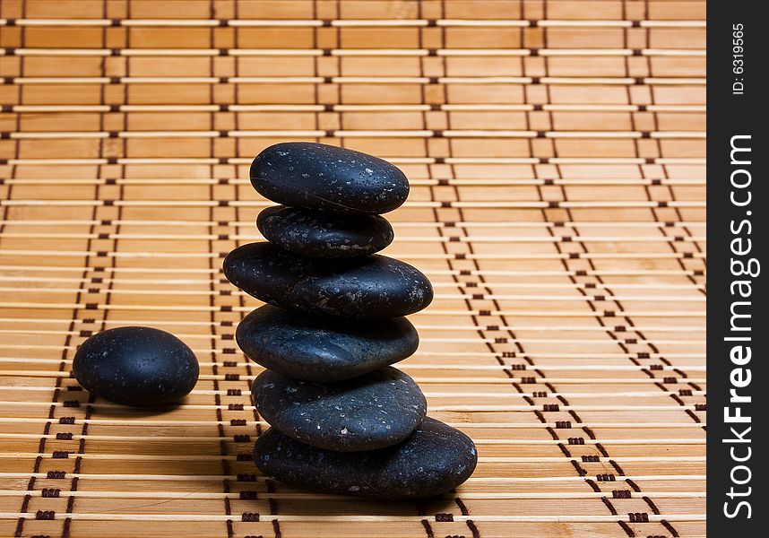 Cairn of black stones on bamboo mat
