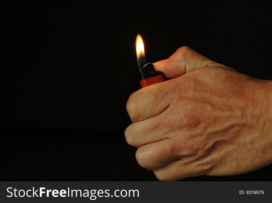 Male hand with burned disposable plastic lighter on dark background. Male hand with burned disposable plastic lighter on dark background