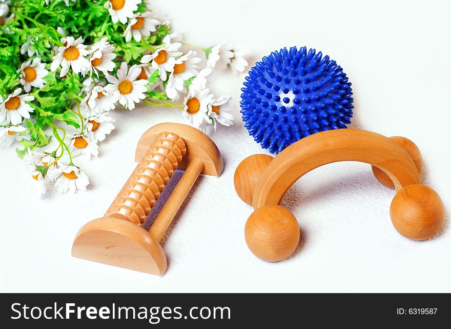 Three massage utensils, as ball, roller on white background with flowers