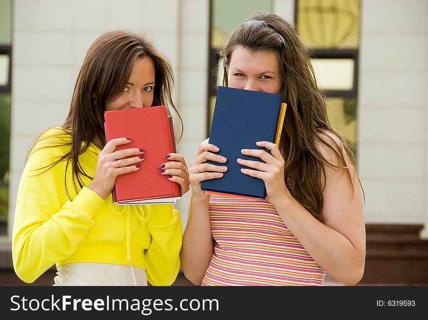 Two cute students hold books in their hands