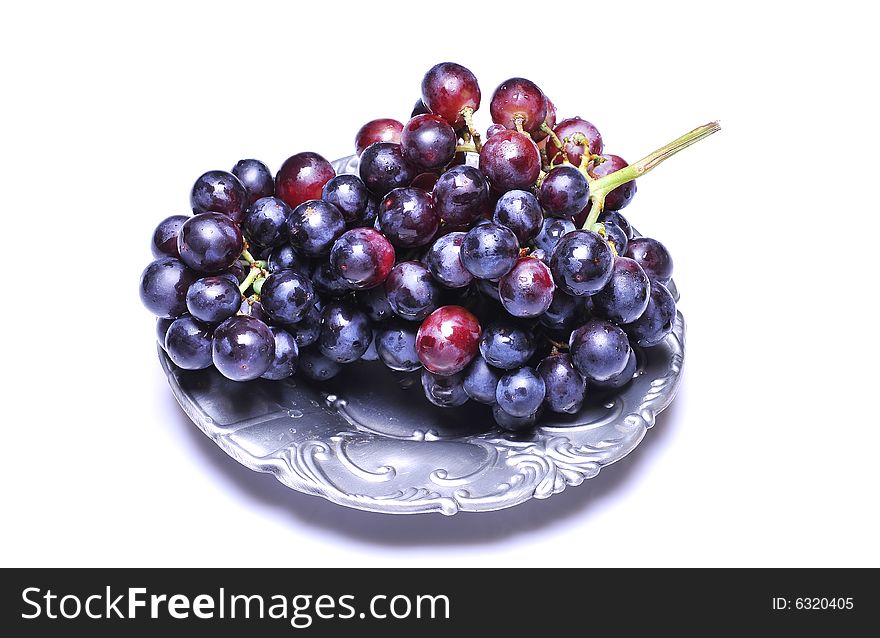 Grapes with drops in plate on white background