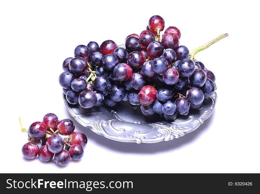 Grapes with drops in plate on white background