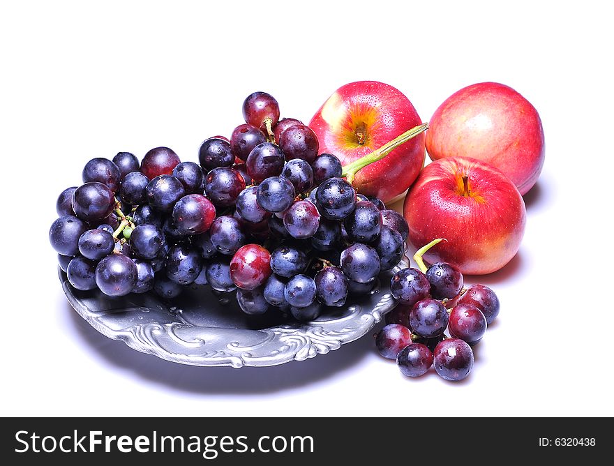 Grapes with apples in plate on white background