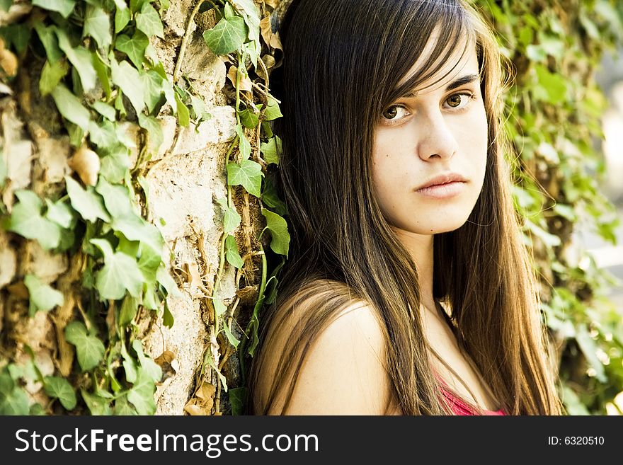 Young woman on wall full of leaves.