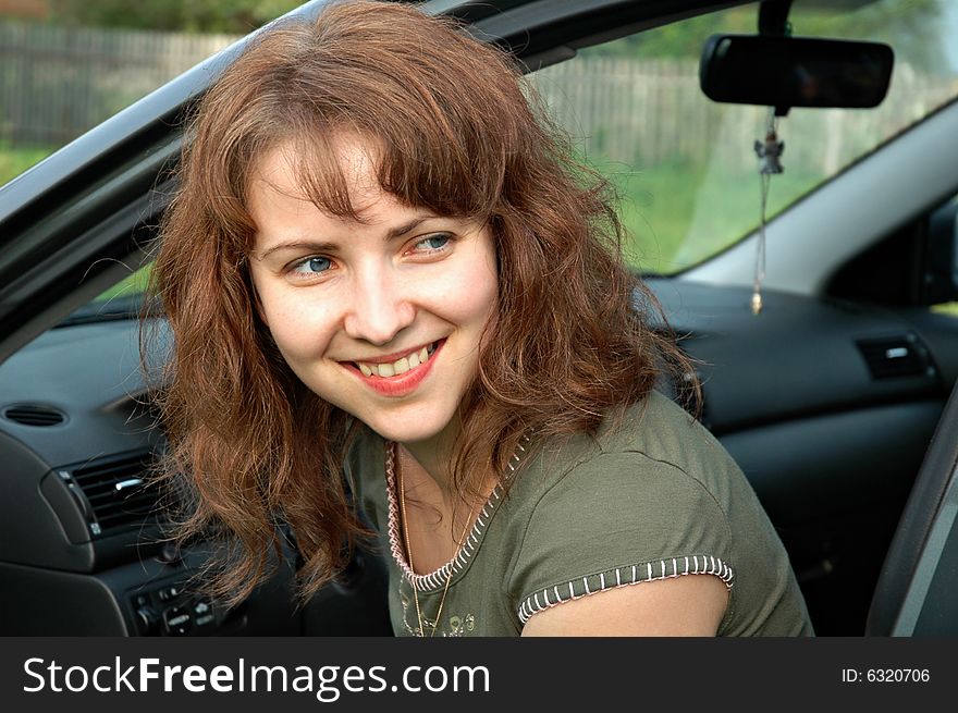 A portrait view of a smiling young woman as she opens a car door. A portrait view of a smiling young woman as she opens a car door.