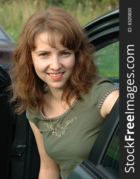 Portrait of smiling beautiful young woman exiting car door.