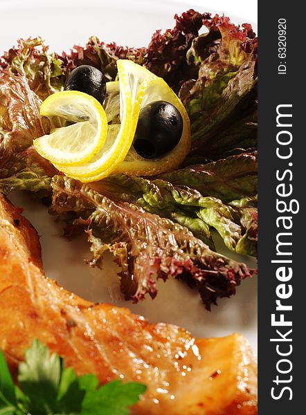 Steak from Filleted Fish (Salmon) with Lemon Slice Olive and Salad on a Plate. Isolated on White Background. Steak from Filleted Fish (Salmon) with Lemon Slice Olive and Salad on a Plate. Isolated on White Background