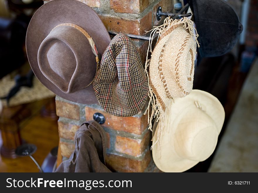 A variety of hats hanging on multiple hooks on a pillar inside the lounge of a modern house.