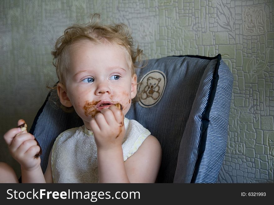 Baby eat chocolate cake on kitchen