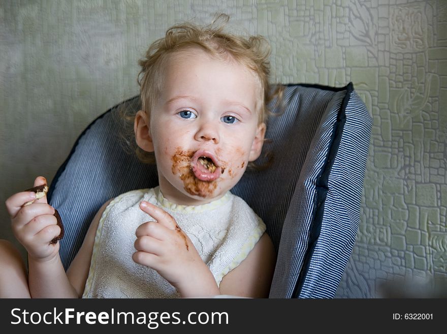 Baby eat chocolate cake on kitchen