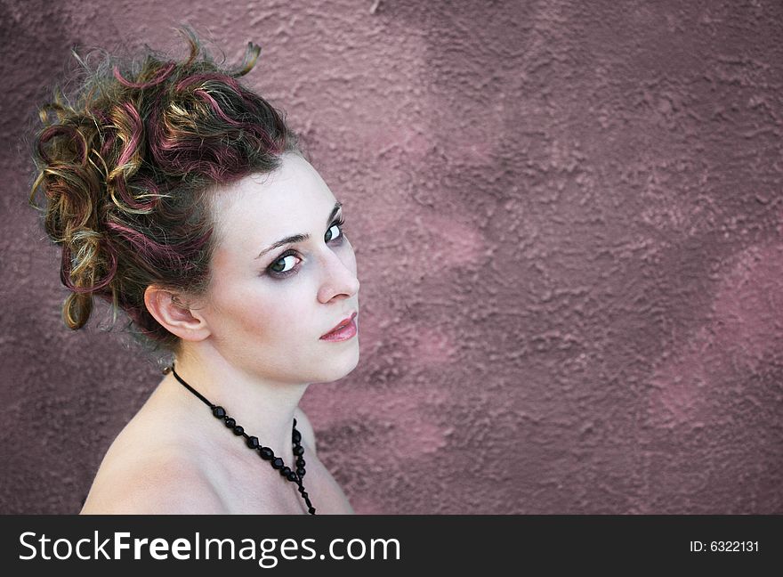 A woman looking at the camera against a gritty urban wall. A woman looking at the camera against a gritty urban wall