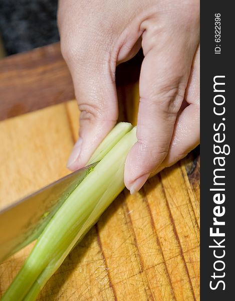A chef cutting through the length of a leek to use as garnish for a gourmet meal. A chef cutting through the length of a leek to use as garnish for a gourmet meal.