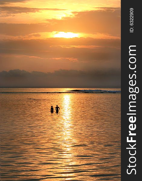 Sunset over lembongen island, bali, indonesia with a couple in the ocean. Sunset over lembongen island, bali, indonesia with a couple in the ocean