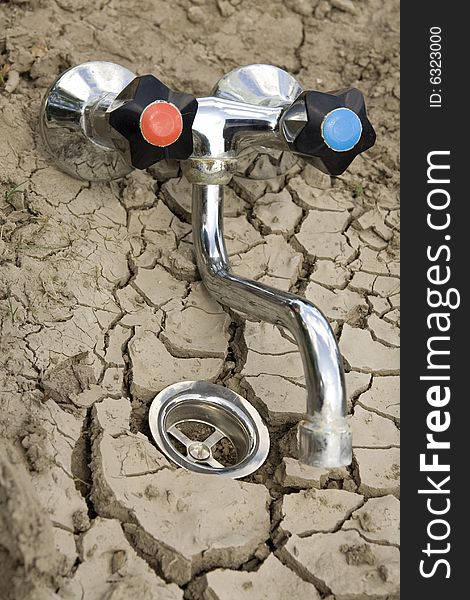 Global Warming Metaphor - dry ground with water outflow and draw-off tap