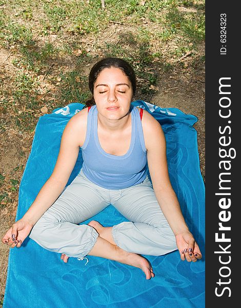 Pretty girl, relaxing on a blue towel in park, meditating. Pretty girl, relaxing on a blue towel in park, meditating