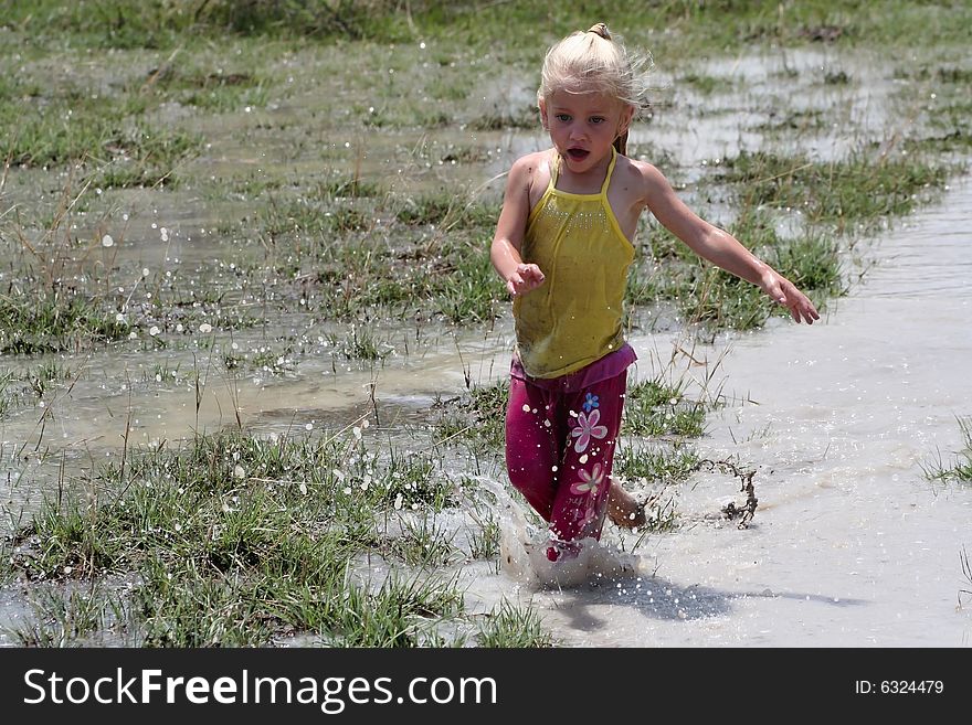 Little girl playing in muddy water dirtying her clothes. Little girl playing in muddy water dirtying her clothes