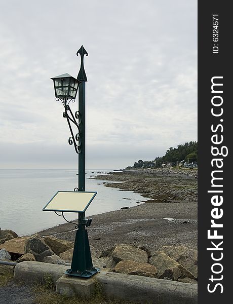 A lantern on the seashore with a blank sign that can be used to post a message. A lantern on the seashore with a blank sign that can be used to post a message