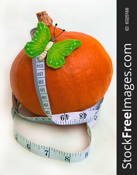 The beautiful green butterfly on a pumpkin and a white measuring tape. A healthy food. Diet. The beautiful green butterfly on a pumpkin and a white measuring tape. A healthy food. Diet