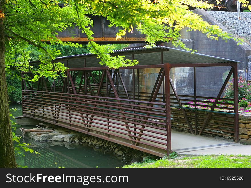 A covered bridge over water with a green tree framing it.