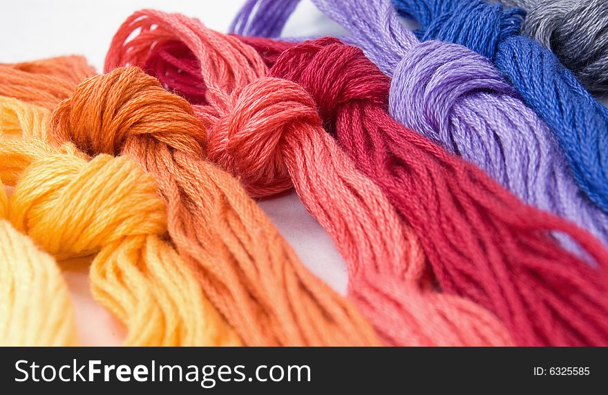 Close-up of several buns of color sewing lying on a white background. Close-up of several buns of color sewing lying on a white background