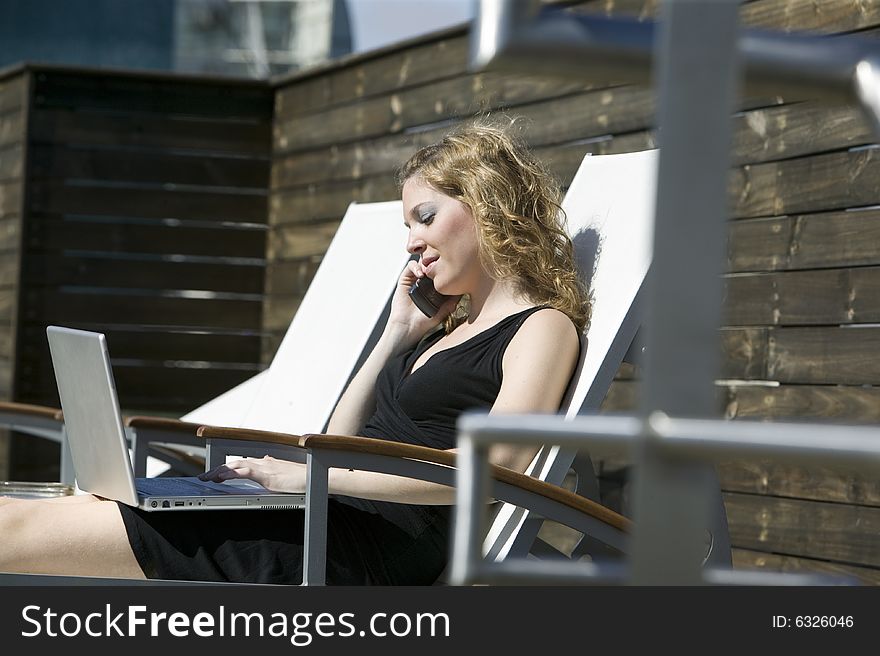 Woman on pool chair working on her computer. Woman on pool chair working on her computer
