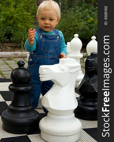 The little boy plays the big chessmen. The little boy plays the big chessmen.