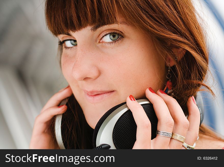 Pretty young girl holding big headphones listening to music. Pretty young girl holding big headphones listening to music