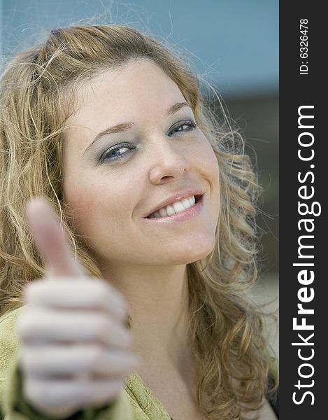 Young blonde woman giving thumbs up sign