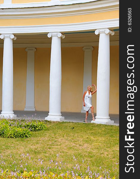 Young woman in white dress against antique colonnade