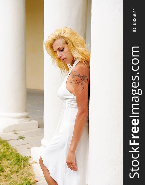 Young woman in white dress against antique colonnade