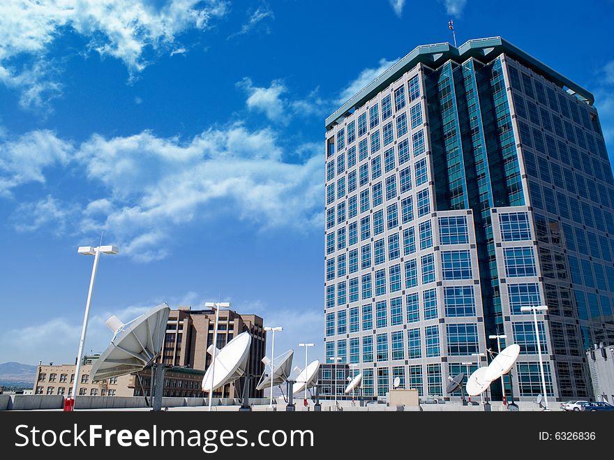 A modern building with rows of satellites in the foreground.